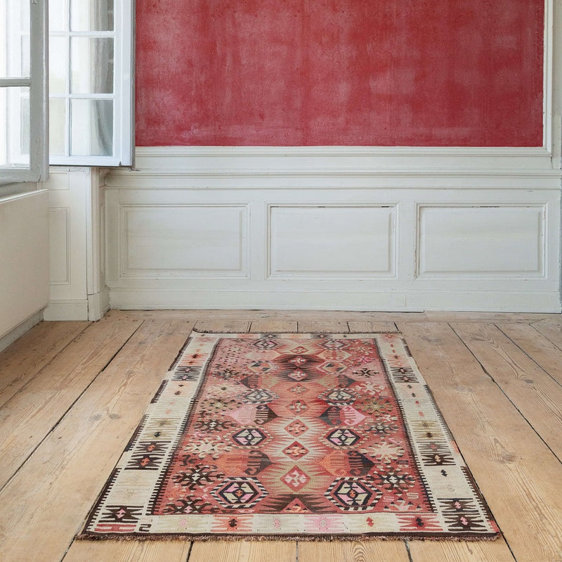 small kilim from mutte storm in a room with a red wall
